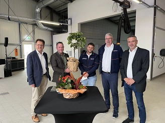 Fünf Personen posieren vor einem Tisch mit Blumen und einem kleinen Baum.