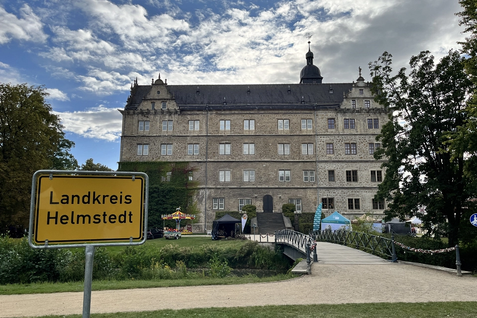 Schild mit Aufschrift "Landkreis Helmstedt" vor einem großen, hellen Renaissance-Schloss.