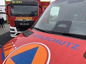 Rotes Feuerwehrfahrzeug mit dem Schriftzug "FEUERWEHR" und "ZIVILSCHUTZ" im Kreis.